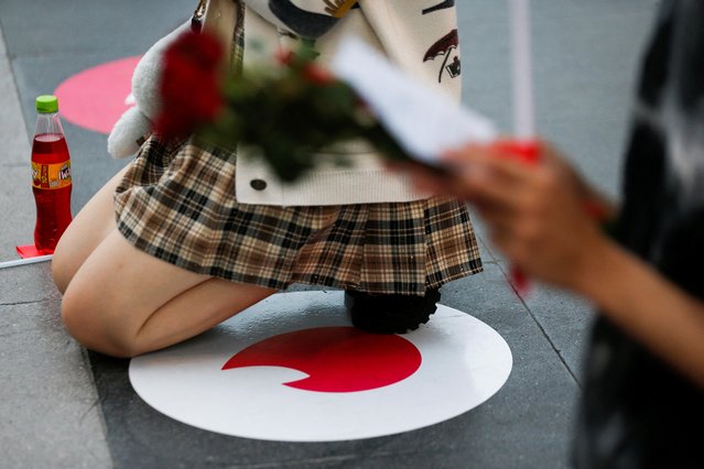 A woman kneels down to pray at a “Pray and swipe right” event organised by online dating app Tinder, with social-distancing stickers featuring its flame logo on the praying ground, a photo booth where people can take profile pictures for their new accounts, and free offering sets, at the Trimuriti shrine on Valentine's Day in Bangkok, Thailand February 14, 2022. (Photo by Soe Zeya Tun/Reuters)