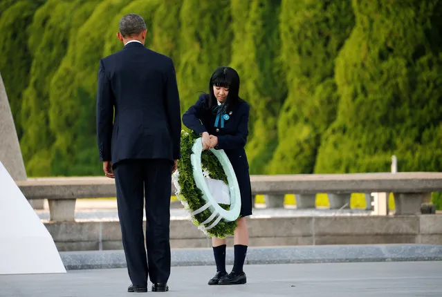 U.S. President Barack Obama (L) receives a wreath from a student in front of a cenotaph at Hiroshima Peace Memorial Park in Hiroshima, Japan May 27, 2016. (Photo by Carlos Barria/Reuters)