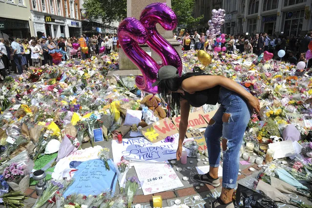 A young woman views of flower tributes  for the victims of Monday's explosion at St Ann's square in central Manchester, England Thursday May 25 2017. More than 20 people were killed in an explosion following a Ariana Grande concert at the Manchester Arena Monday evening. (Photo by Rui Vieira/AP Photo)