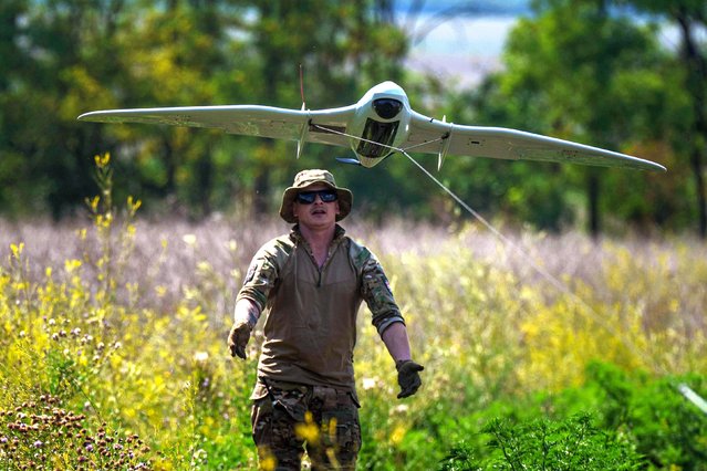 A Ukrainian serviceman of the Ochi reconnaissance unit launches a Furia drone to fly over Russian positions at the frontline in Donetsk region, Ukraine, on Sunday, June 30, 2024. (Photo by Evgeniy Maloletka/AP Photo)