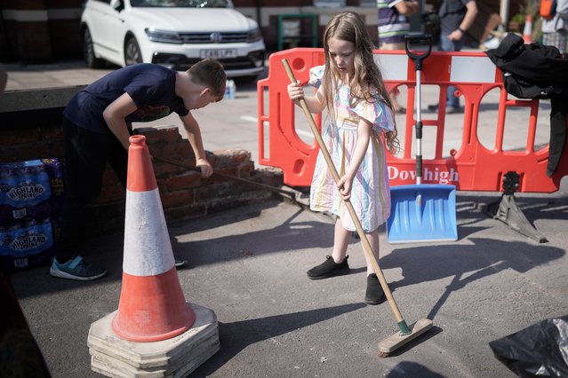 Local children Sebastian Taylor, aged 10, and his sister Evelyn Taylor, aged seven, sweep up the street outside a Mosque that was attacked last night during civil disorder on July 31, 2024 in Southport, England. Members of Far Right groups rioted outside a mosque in Southport overnight as the Southport Community gathered at a vigil to remember three children stabbed to death at a holiday club on Monday. Southport's MP Patrick Hurley said the mob had “disrespected the victims' families” and the Prime Minister vowed the rioters will face the “full force of the law”. (Photo by Christopher Furlong/Getty Images)