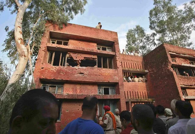 Onlookers and Indian security personnel stand at the site of a gunfight in Dinanagar town in Gurdaspur district of Punjab, India, July 27, 2015. (Photo by Mukesh Gupta/Reuters)