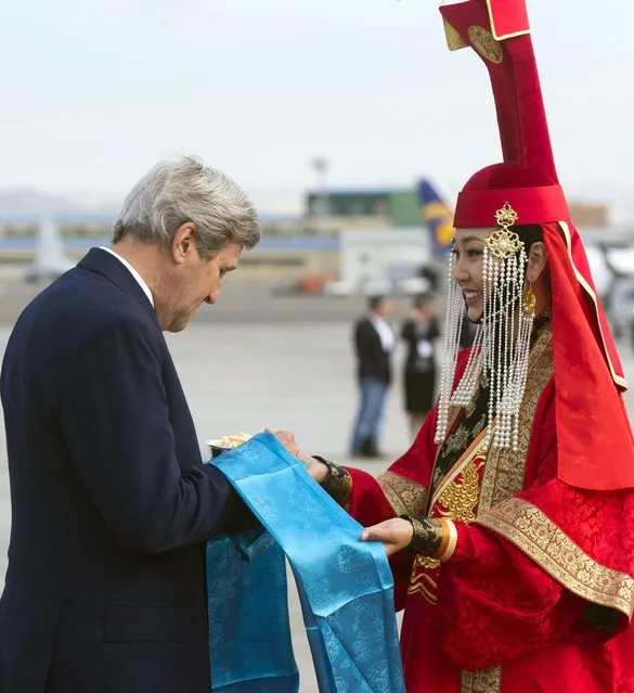US Secretary of State John Kerry samples cheese curds alongside a woman in traditional attire as he disembarks from his airplane upon arrival at Chinggis Khaan International Airport in Ulaanbaatar, Mongolia, June 5, 2016. (Photo by Saul Loeb/Pool Photo via AP Photo)