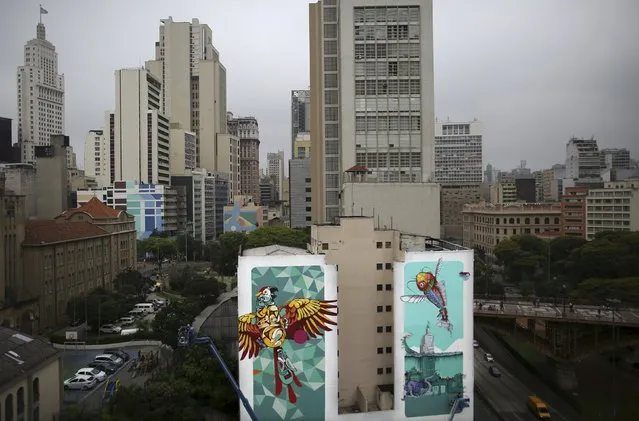 Artists Binho (R) from Brazil and Suiko from Japan paint their works on a building during the International Festival of Street Art in Sao Paulo October 24, 2015. (Photo by Nacho Doce/Reuters)