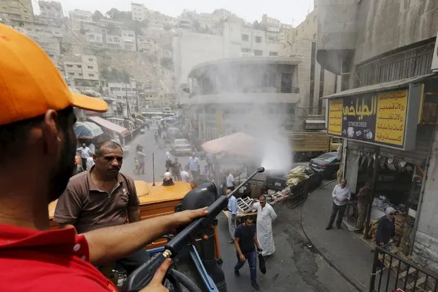 Greater Amman Municipality personnel spray people with a water sprinkler in order to cool them down as part of measures to ease the effect of a heatwave, in Amman, Jordan, August 3, 2015. (Photo by Muhammad Hamed/Reuters)