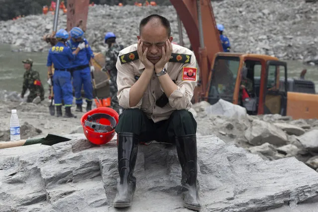 A rescue worker takes a nap at the site of a landslide in Xinmo village in Maoxian County in southwestern China's Sichuan Province, Sunday, June 25, 2017. (Photo by Ng Han Guan/AP Photo)