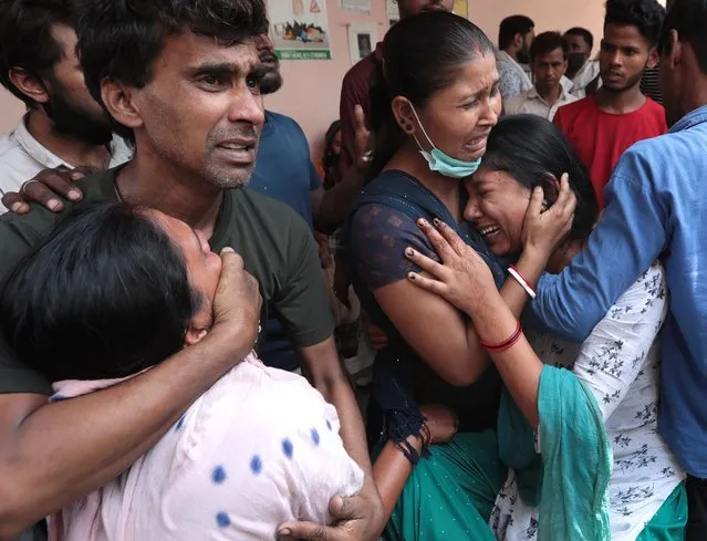 Relatives of one of the victims of a commercial building fire mourn outside a morgue at Sanjay Gandhi Memorial Hospital in the outskirts of New Delhi, India, 14 May 2022. Local police confirmed at least 27 people died after a fire broke out in a commercial building in Mundka in the evening of 13 May. (Photo by Rajat Gupta/EPA/EFE)