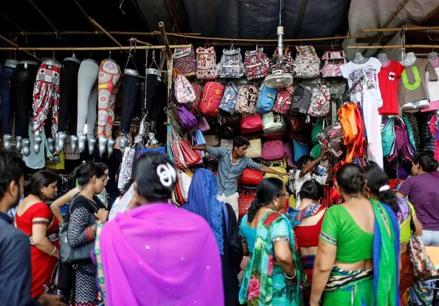 People shop for bags and clothes at roadside shops in a market in Mumbai, India June 13, 2016. (Photo by Danish Siddiqui/Reuters)