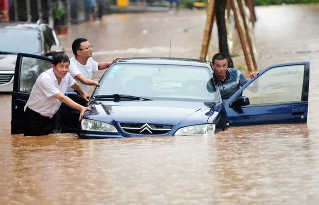 People attempt to push a car through flood waters in Jiujiang, central China's Jiangxi province, 15 June 2016. Atleast 15 people are dead and 10 missing after heavy storms caused flooding in southern China. (Photo by Hu Guolin/EPA)