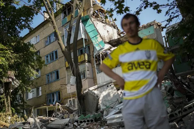 A local resident stands next to a residential building heavily damaged in a Russian bombing in Bakhmut, eastern Ukraine, Monday, May 30, 2022. (Photo by Francisco Seco/AP Photo)