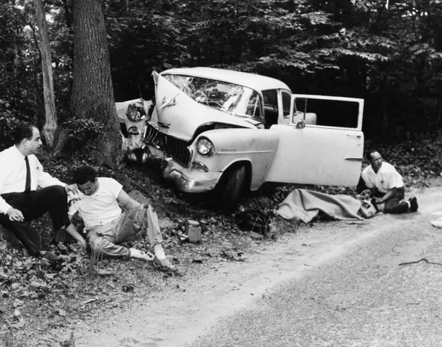 Mara Scherbatoff, New York bureau chief for French magazine Paris Match, lies fatally injured under a blanket alongside car in which she was pursuing Marilyn Monroe and Arthur Miller near his Roxbury, Conn., home on June 29, 1956. Unidentified man comforts her before she was taken to the hospital where she died. Ira Slade, second from left, who was driving the car, is aided by his brother Paul, a Paris Match photographer, who was not in the car. No reason was immediately known why the car left the road and hit a tree. (Photo by AP Photo)