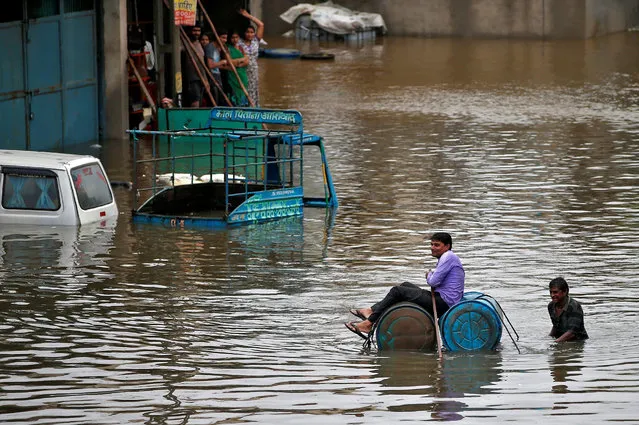 A man uses a makeshift raft to move out of a flooded neighbourhood after heavy rains in Ahmedabad, July 27, 2017. (Photo by Amit Dave/Reuters)