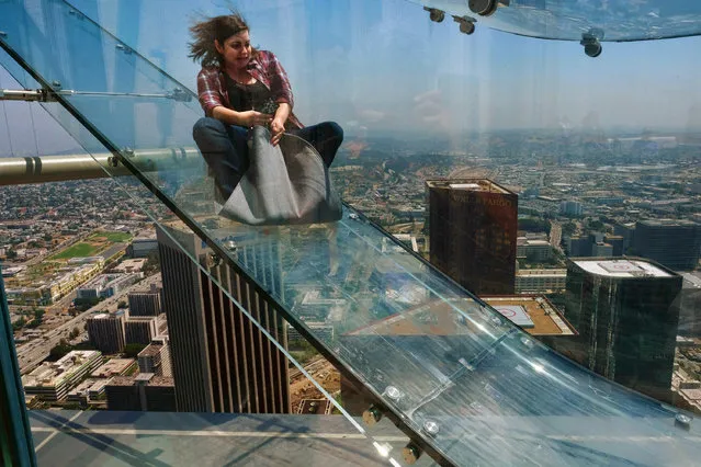 A member of the media rides down a glass slide during a media preview at the U.S. Bank Tower building in downtown Los Angeles on Thursday, June 23, 2016. Starting this weekend, thrill-seekers can begin taking the Skyslide, a 1,000 feet high slide, perched on the outside of the tallest skyscraper west of the Mississippi. (Photo by Richard Vogel/AP Photo)