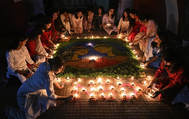 Students light earthen oil lamps during the celebrations to mark Diwali, the Hindu festival of lights, in Guwahati on October 31, 2024. (Photo by Biju Boro/AFP Photo)