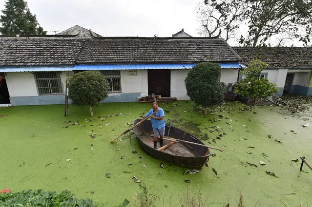 A man rows a boat near a flooded house in Hefei, Anhui Province, China, July 9, 2016. (Photo by Reuters/Stringer)