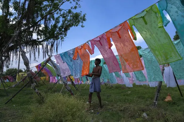 A dhobi, or a washerman hangs cloths for drying after washing them on the banks of the River Gomti in Lucknow, northern Uttar Pradesh state, India, Sunday, July 17, 2022. Dhobis are traditional laundry workers who wash clothes by hand and dry them in the sun, an occupation which has been in existence for generations. This practice is still popular in many parts of India, despite of modern technology. (Photo by Rajesh Kumar Singh/AP Photo)