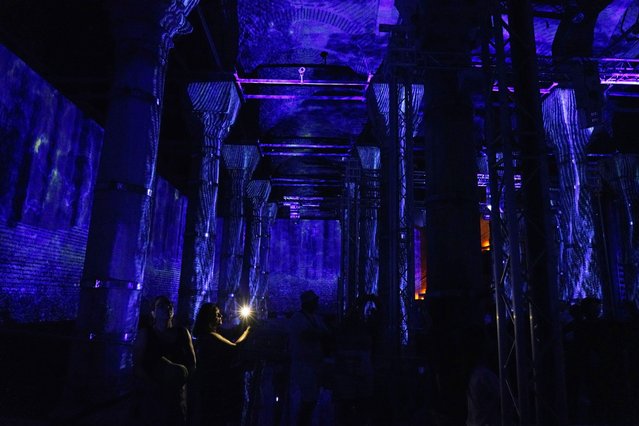 A woman takes a video with a cellphone during a light show at the Serefiye Cistern in Istanbul, Turkey, Sunday, June 26, 2022. (Photo by Jon Gambrell/AP Photo)