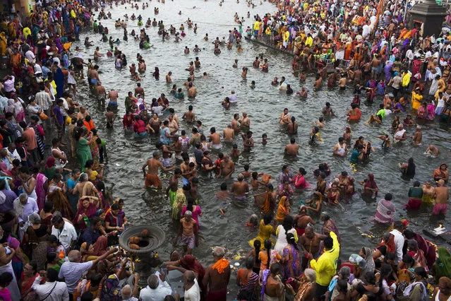 Hindu devotees take holy dip in the River Godavari on the first official day of bathing as part of Kumbh Mela celebrations in Nasik, India, Wednesday, August 26, 2015. Hindus believe that sins accumulated in past and current lives require them to continue the cycle of death and rebirth until they are cleansed. Bathing in sacred waters on the most auspicious day of the Kumbh festival, or Pitcher Festival, believers say rids them of their sins. (Photo by Bernat Armangue/AP Photo)