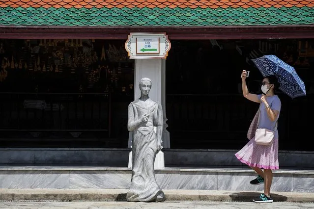 A visitor takes photos next to one of the newly found centuries old ancient stone sculptures on display at the Temple of the Emerald Buddha, in Bangkok, Thailand, 15 July 2022. Thai authorities found more than 130 centuries old ancient stone sculptures during a road construction outside the Grand Palace compound and put them on display at the Temple of the Emerald Buddha. The carved stone statues are believed were used as ballast for the stabilization of Chinese sailing vessels and left in the Thai kingdom in ancient maritime trading times. (Photo by Anusak Laowilas/NurPhoto/Rex Features/Shutterstock)