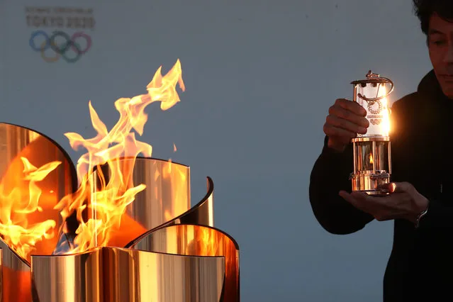 A staff preserves the Olympic flame to the lantern during the 'Flame of Recovery' special exhibition at Aquamarine Park a day after the postponement of the Tokyo 2020 Olympic and Paralympic Games announced due to the coronavirus pandemic on March 25, 2020 in Iwaki, Fukushima, Japan. (Photo by Clive Rose/Getty Images)