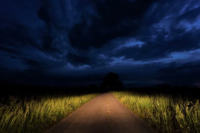 In this photo taken with a long exposure, dark clouds pass over a street illuminated by a car in Ebing, Germany, Friday, May 20, 2022. The German Weather Service (DWD) expects thunderstorms for parts of Bavaria in the evening hours. (Photo by Nicolas Armer/dpa via AP Photo)