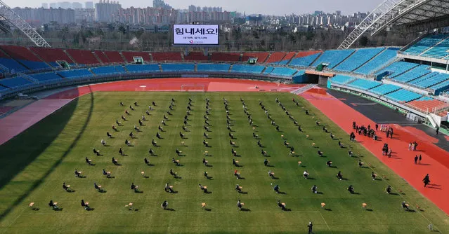 This picture taken on April 4, 2020 shows job applicants taking a written exam on a football field during a recruitment test for the city-run Ansan Urban Corporation at the Wa Stadium in Ansan, south of Seoul. The corporation decided to hold the test outdoors as part of efforts to prevent the spread of the COVID-19 coronavirus. (Photo by Yonhap/AFP Photo)