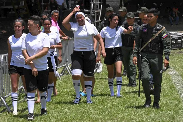 Inmates members of Tocuyito team are escorted by members of the Bolivarian National Guard (GNB) before their Penitentiary Rugby Tournament match organized by the Santa Teresa Foundation at the sports field Hacienda Santa Teresa in El Consejo, Aragua State, Venezuela, on September 1, 2022. For the first time, the Santa Teresa Foundation is organizing a women's prison rugby tournament as part of a program called Alcatraz, which aims to give female prisoners the opportunity to reintegrate into civil society. (Photo by Yuri Cortez/AFP Photo)