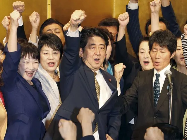 Japan's Prime Minister Shinzo Abe (C) raises his fist as he shouts slogans with his party lawmakers during a kickoff ceremony for the party chief election in Tokyo, in this photo taken by Kyodo September 8, 2015. Abe won a rare second consecutive term on Tuesday as ruling party chief, and hence premier, pledging to retain focus on reviving the world's third-biggest economy and deepen debate on revising its pacifist constitution. (Photo by Reuters/Kyodo News)