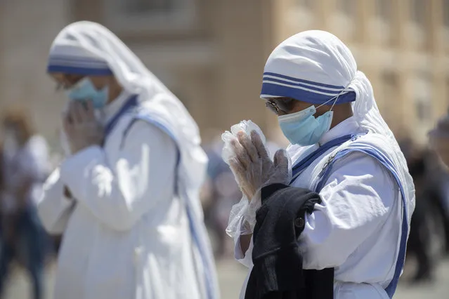 Nuns wearing gloves and masks to prevent the spread of COVID-19 pray in St. Peter's Square at the Vatican, Sunday, May 31, 2020. Pope Francis has cheerfully greeted people in St. Peter’s Square on Sunday, as he resumed his practice of speaking to the faithful there for the first time since lockdown began in Italy and at the Vatican in early March. Instead of the tens of thousands of people who might have turned out on a similarly brilliantly sunny day like this Sunday, in pre-pandemic times, perhaps a few hundred came to the square, standing well apart from others or in small family groups. (Photo by Alessandra Tarantino/AP Photo)
