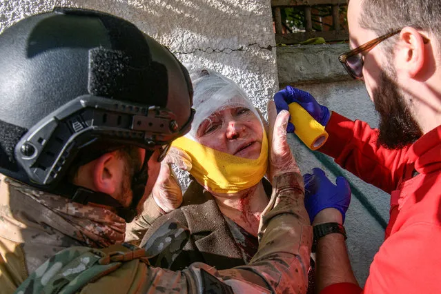 Paramedics help a woman injured during a Russian missile strike, amid Russia's attack on Ukraine, in Kyiv, Ukraine on October 10, 2022. (Photo by Vladyslav Musiienko/Reuters)