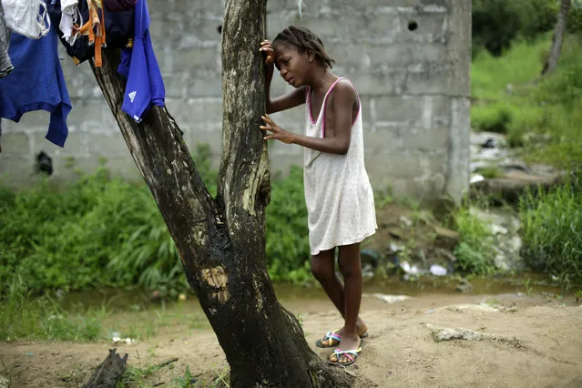 Mercy Kennedy, 9, cries Thursday October 2,  2014.  as community activists approach her outside her home on 72nd SKD Boulevard in Monrovia, Liberia, a day after her mother was taken away by an ambulance to an Ebola ward. Neighbors wailed Thursday upon learning that Mercy's mother had died; she was among the cluster of cases that includes Thomas Eric Duncan, a Liberian man now hospitalized in Texas. (Photo by Jerome Delay/AP Photo)