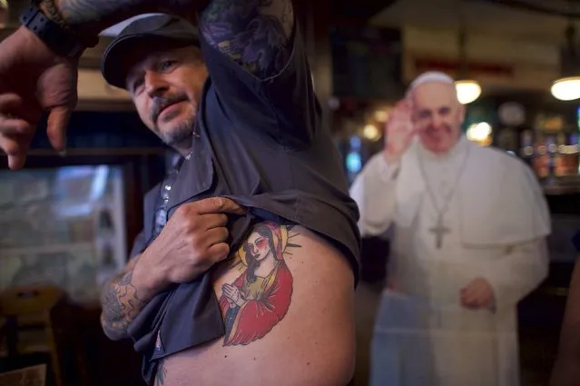 Hugh Morgan, from Las Vegas, shows his Japanese inspired Virgin Mary tattoo, in front of a cardboard cut-out of Pope Francis, during an event organised by Christa Scalies, the co-creator of the Pop-Up Pope, in Fado Irish Pub & Restaurant in Philadelphia, Pennsylvania, September 16, 2015. (Photo by Mark Makela/Reuters)