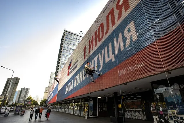 In this photo taken on Monday, June 22, 2020, a worker cleans an electronic scoreboard reading “All-Russia voting, July 1, Our Constitution” in the center of Moscow, Russia. Russian authorities seem to be pulling out all the stops to get people to vote on constitutional amendments that would enable President Vladimir Putin to stay in office until 2036. The nationwide vote begins Thursday and lasts for a week. (Photo by Alexander Zemlianichenko/AP Photo)