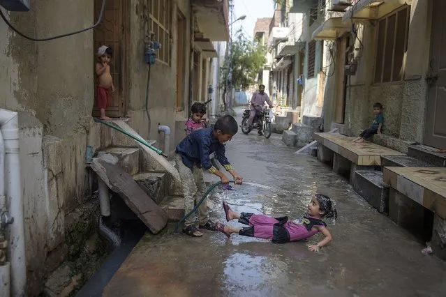 Children play with a water pipe to cool off on a street during hot summer in Rawalpindi on July 8, 2020. (Photo by Farooq Naeem/AFP Photo)
