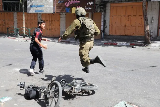An Israeli soldier runs after a Palestinian youth during clashes in the area of Bab al-Zawiya in the centre of the city of Hebron in the occupied West Bank on September 29, 2022. (Photo by Mosab Shawer/AFP Photo)