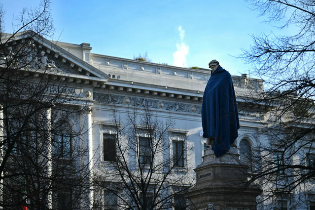 A statue of Leonardo Da Vinci is covered with a blue blanket as part of a campaign of communication by Italian foundation Progetto Arca Onlus that helps homless and lonely people by listening to them and providing basic necessities, on February 14, 2024 Piazza della Scala in Milan. The operation of sensibilization is called “Cover the most important people of the city” to highlight the situation of homeless. (Photo by Gabriel Bouys/AFP Photo)