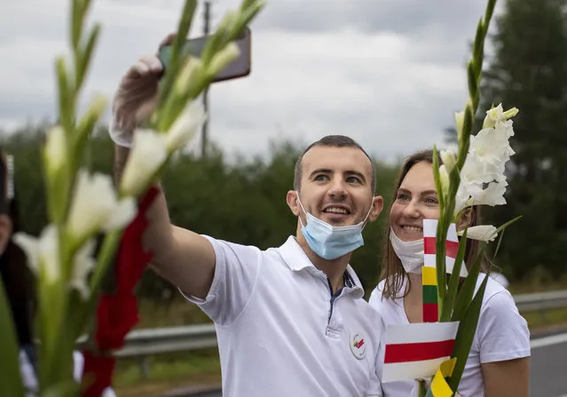 Supporters of Belarus opposition from Lithuania hold historical Belarusian flags and takes a selfie during the “Freedom Way”, a human chain of about 50,000 strong from Vilnius to the Belarusian border, during a protest near Medininkai, Lithuanian-Belarusian border crossing east of Vilnius, Lithuania, Sunday, August 23, 2020. (Photo by Mindaugas Kulbis/AP Photo)