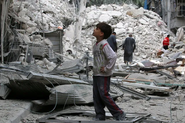 A boy inspects a damaged site after airstrikes on the rebel held Tariq al-Bab neighbourhood of Aleppo, Syria September 23, 2016. (Photo by Abdalrhman Ismail/Reuters)