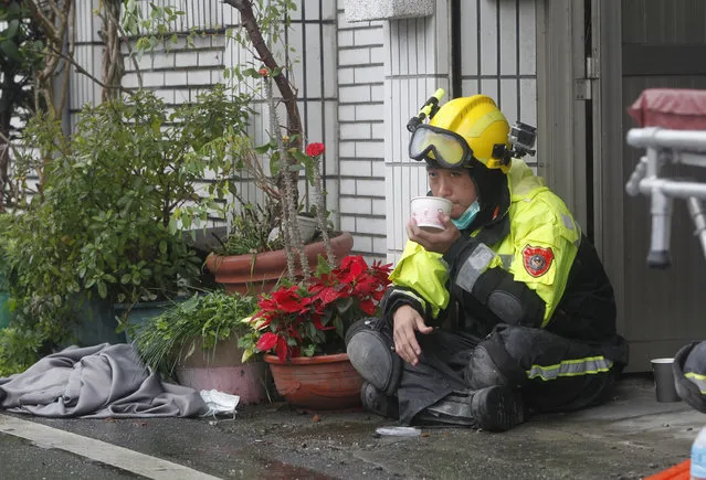 A rescuer takes a rest as searches continue for missing people in a collapsed apartment building following a strong earthquake in Hualien County, eastern Taiwan, Thursday, February 8, 2018. A magnitude 6.4 earthquake struck late Tuesday night caused several buildings to cave in and tilt dangerously. (Photo by Chiang Ying-ying/AP Photo)