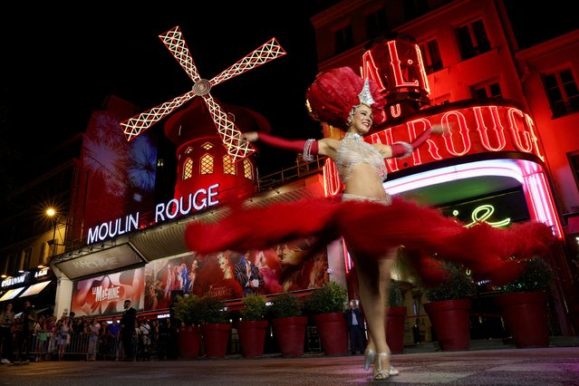 A French Cancan dancer performs in front of the Moulin Rouge cabaret during celebrations marking the restart of its iconic windmill with red sails, in Paris, France on July 10, 2025. (Photo by Tom Nicholson/Reuters)