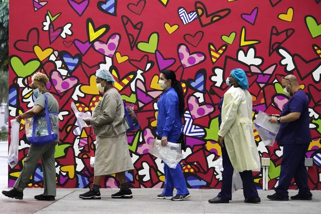 Healthcare workers line up for free personal protective equipment in front of a mural by artist Romero Britto at Jackson Memorial Hospital, Tuesday, September 22, 2020, in Miami. Hundreds of workers lined up for the PPE given out by the New York nonprofit Cut Red Tape 4 Heroes. (Photo by Wilfredo Lee/AP Photo)