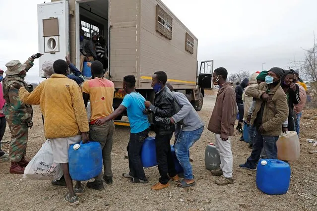 A South African National Defence Force (SANDF) member directs suspected undocumented Zimbabwean nationals into a vehicle after attempting to illegally cross the border fence to smuggle goods and fuel into Zimbabwe from South Africa near the Beitbridge border post, near Musina, on October 2, 2020. (Photo by Phill Magakoe/AFP Photo)