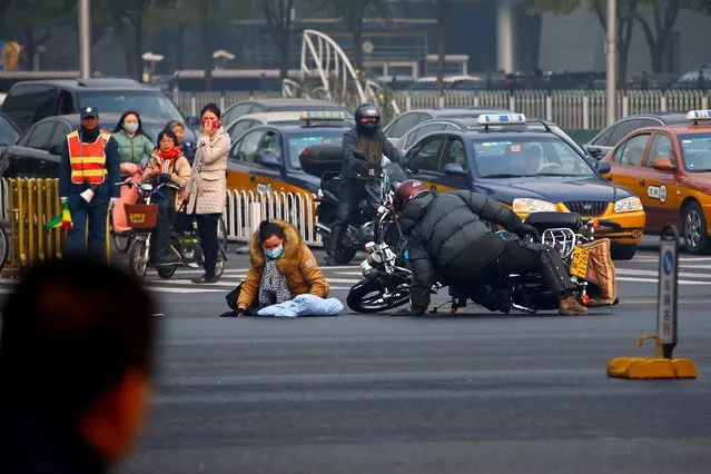 A woman falls down from her electronic bike as a man falls from his motorbike in a traffic accident on a street in centre Beijing, November 26, 2014. (Photo by Petar Kujundzic/Reuters)