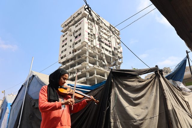 A student plays the violin during a music class in a camp for displaced Palestinians in the northern Al-Rimal neighborhood of Gaza City on July 10, 2025. (Photo by Omar Al-Qattaa/AFP Photo)