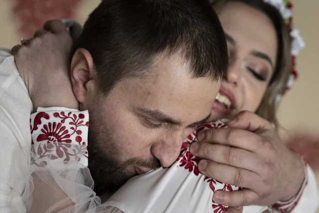 Ukrainian soldier Vitalii Khroniuk kisses his wife Anna Sokurenko during their wedding ceremony in Kyiv, Ukraine, Tuesday, February 7, 2023. As Khroniuk lay facedown on the ground taking cover from Russian artillery fire, the Ukrainian solider had just one regret: He had never had a child. Aware that he could die at any moment, the 29-year-old decided to try cryopreservation – the process of freezing sperm or eggs that some Ukrainian soldiers are turning to as they face the possibility that they might never go home. (Photo by Evgeniy Maloletka/AP Photo)