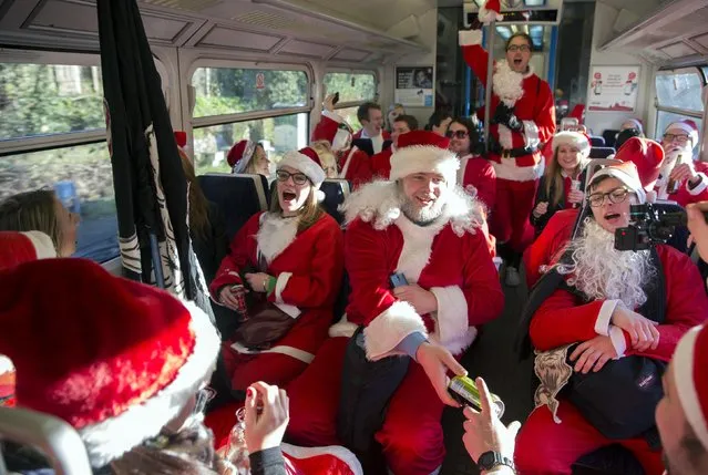 Participants dressed in Santa costumes sing on a train during the annual SantaCon event in London December 6, 2014. (Photo by Neil Hall/Reuters)