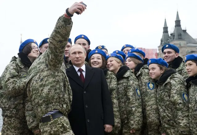 Russian President Vladimir Putin (C) poses for a selfie with young activists at the Red Square in Moscow on November 4, 2015 during celebrations for National Unity Day marking the 403rd anniversary of the 1612 expulsion of Polish occupation forces from the Kremlin. (Photo by Natalia Kolesnikova/AFP Photo)