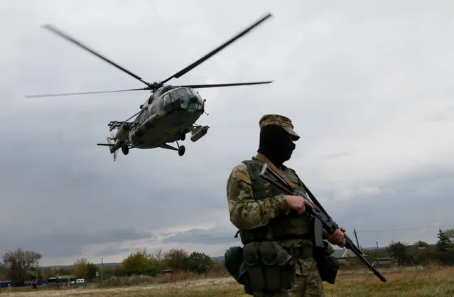 A member of Ukrainian armed forces stands guard while a military helicopter takes off near the town Novoaidar in Luhansk Region, Ukraine, October 9, 2016. (Photo by Valentyn Ogirenko/Reuters)