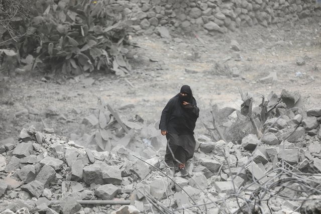 A woman walks on debris at the site of a U.S. strike in Sanaa, Yemen on March 24, 2025. (Photo by Khaled Abdullah/Reuters)