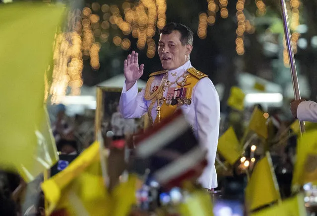 Thai King Maha Vajiralongkorn greets supporters as he walks to participate in a candle lighting ceremony to mark the anniversary of the birth of late King Bhumibol Adulyadej, at Sanam Luang ceremonial ground in Bangkok, Thailand, Saturday, December 5, 2020. Thousands of yellow-clad supporters greeted Thailand's king in Bangkok on Saturday as he led a birthday commemoration for his revered late father, the latest in a series of public appearances at a time of unprecedented challenge to the monarchy from student-led protestors. (Photo by Gemunu Amarasinghe/AP Photo)